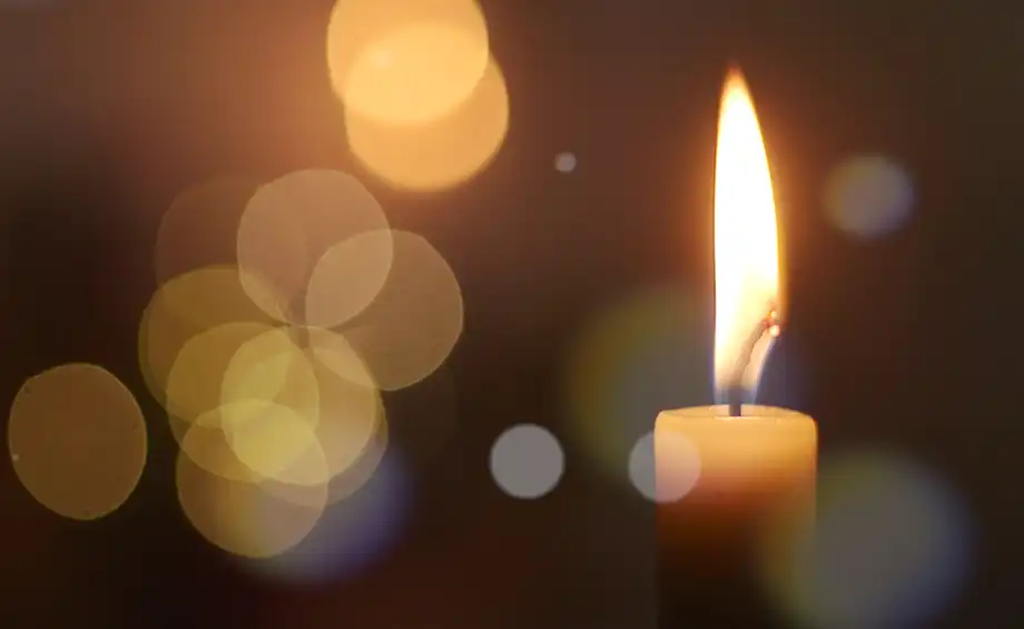 Eine Kerzenflamme bei Nacht mit Bokeh auf dunklem Hintergrund